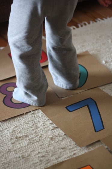 child jumping on cardboard hopscotch on carpet
