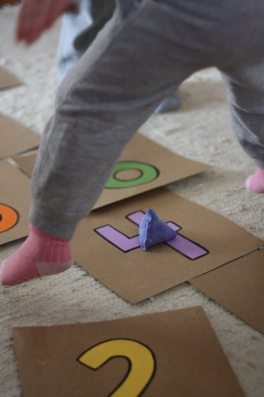 little girl jumping over beanbag on number 4 square