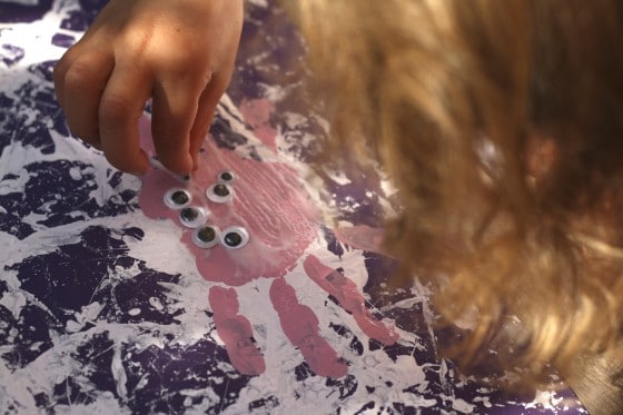 pressing eyes onto pink handprint spider