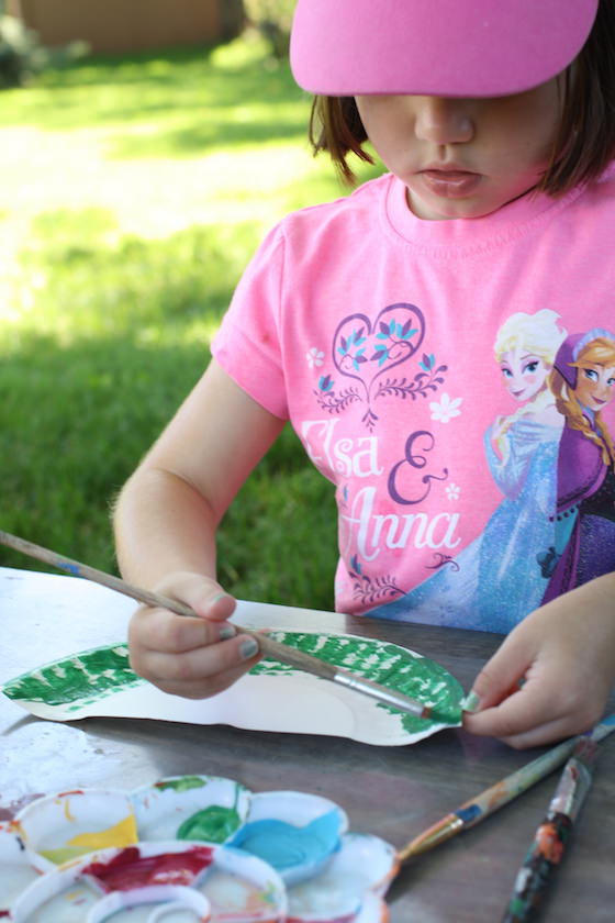 Child painting edge of a paper plate green