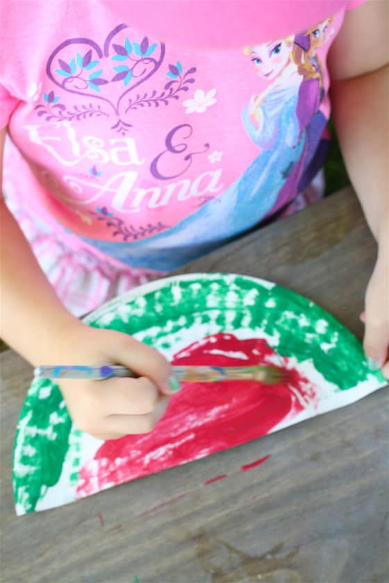 child making a watermelon out of a paper plate