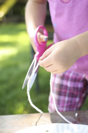 child cutting yarn for dream catcher