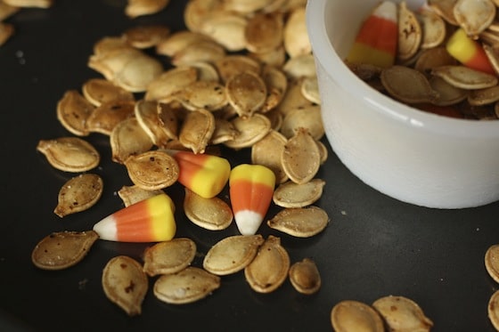 candy corn and roasted pumpkin seeds in bowl on baking sheet