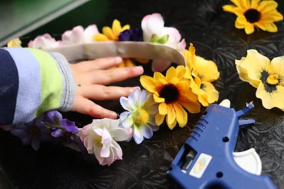 child gluing flowers to waistband elastic to make a flowered tiara for dress up play