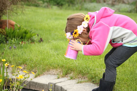 hild looking into pond through homemade toy binoculars