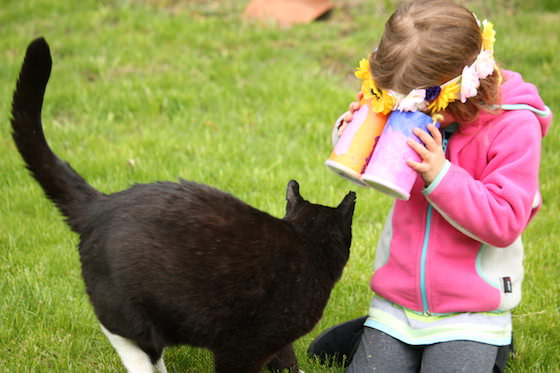 kid looking at cat through toy binoculars