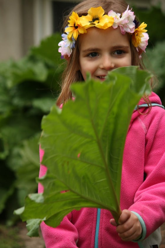 child wearing homemade tiara and holding huge rhubarb leaf