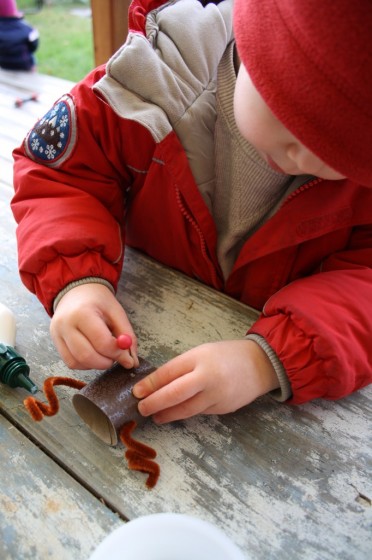 toddler gluing red nose on reindeer ornament