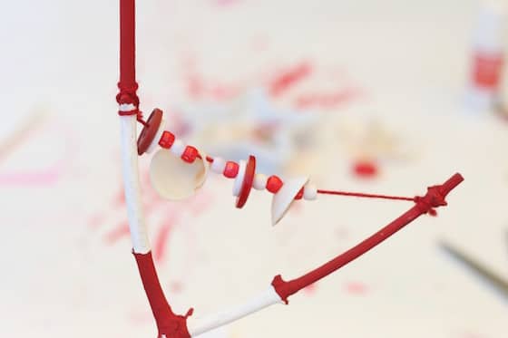 Y-shaped stick painted red and white, and strung with red and white beads, buttons and shells