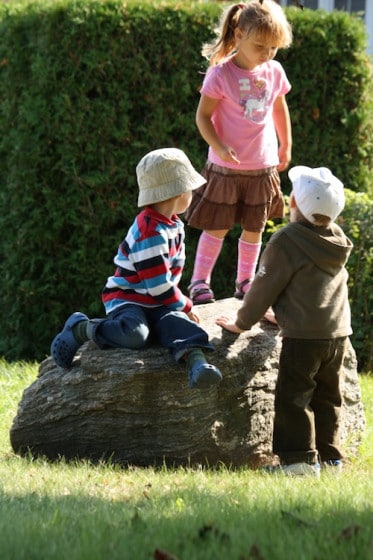 preschoolers balancing on large rock outdoors