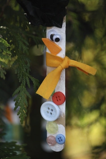 Popsicle stick snowman ornament hanging in christmas tree