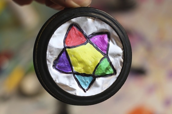 colourful star on tin foil in mason jar lid painted black