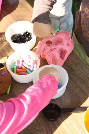 kids pressing beads into pink play dough