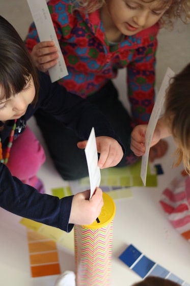 preschoolers dropping paint swatches into pringles can