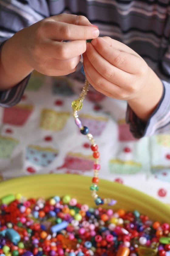 preschooler threading beads on to pipe cleaners