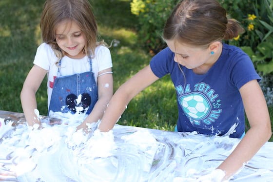 kids cleaning art table with shaving cream