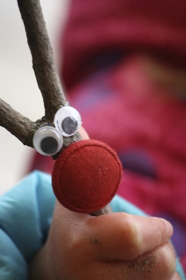 close up of twig reindeer with large red button nose and google eyes 