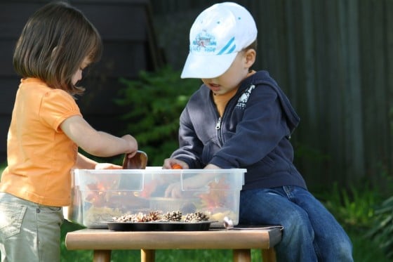 toddlers concentrating on scooping in sensory bin