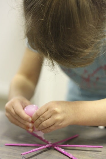 adding glitter glue to craft stick snowflake ornament