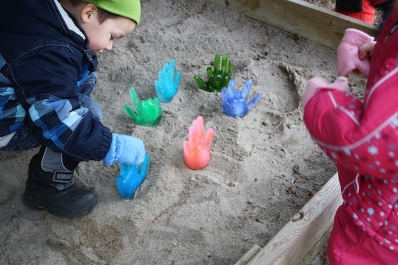 children discovering icy hands in sandbox