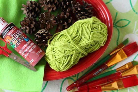 pinecones, yarn and red paint on green apple table cloth