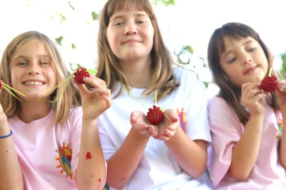 girls holding pinecone necklaces