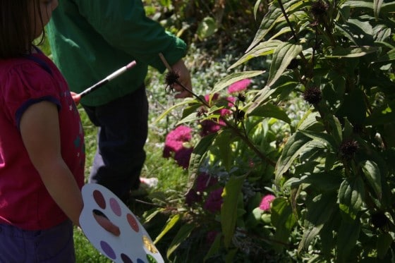 toddlers painting the flowers in the garden with pretend paint palettes