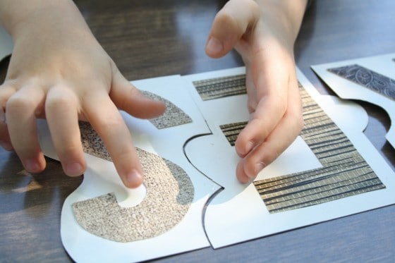 closeup toddlers hands putting puzzle together