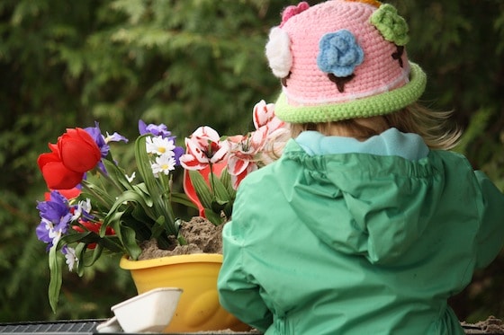 girl playing with artificial flowers in the sandbox