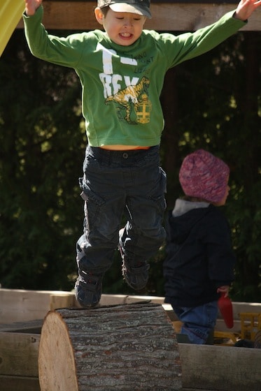 4 year old boy jumping off a play log