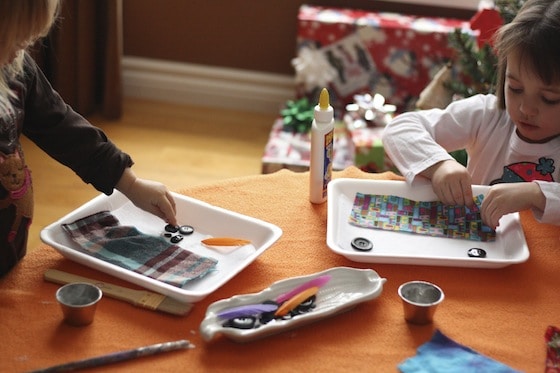 gluing buttons and fabric swatches on to snowman face art projects