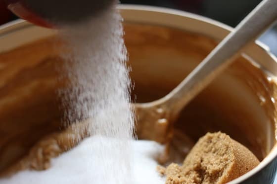 pouring white sugar into peanut butter cookies dough