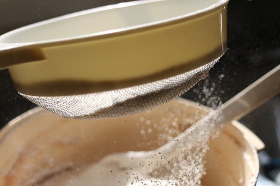 sifting flour into dough for peanut butter cookies