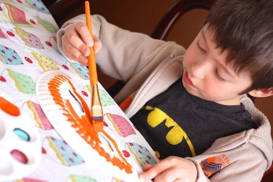 Boy painting a paper plate mask