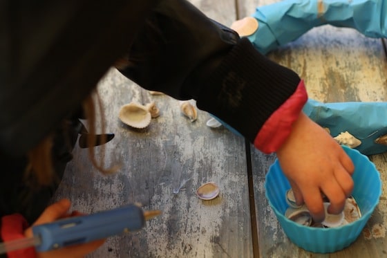 preschoolers gluing shells to the paper bag mermaid crown