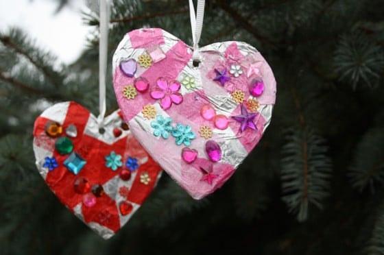 two tin foil hearts decorated with gems hanging in tree