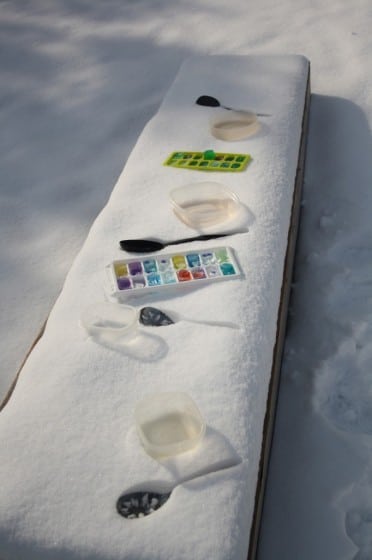 snow-covered bench with coloured ice cubes and plastic spoons