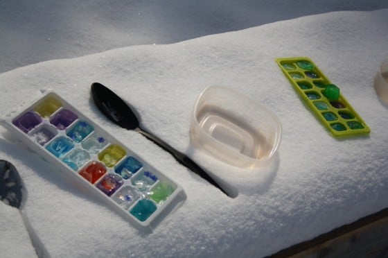 ice cube tray filled with coloured ice cubes on snow