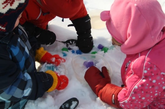 toddlers and preschoolers playing with coloured ice cubes in the snow