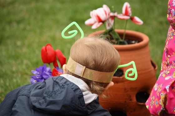 2 year old wearing paper bag band with green pipe cleaner antenae