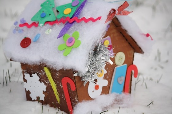 decorated cardboard gingerbread house sitting on snowy ground