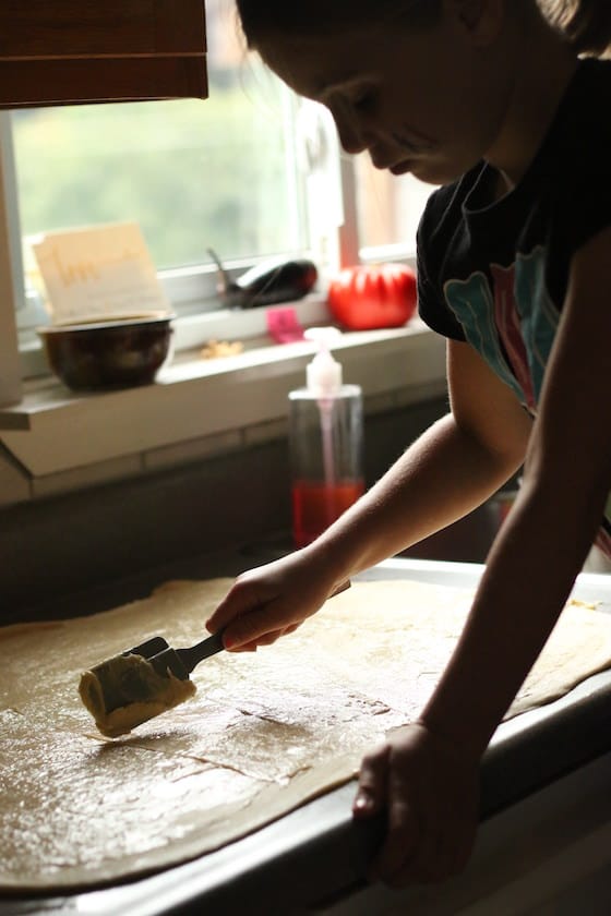 spreading butter over cinnamon roll dough