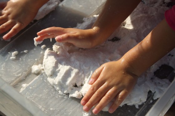 kids patting clean mud into a mud pie