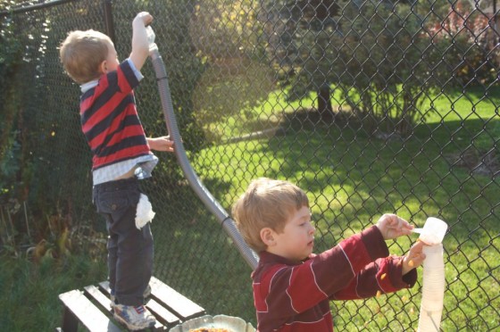 preschool boys pouring corn kernels into hoses