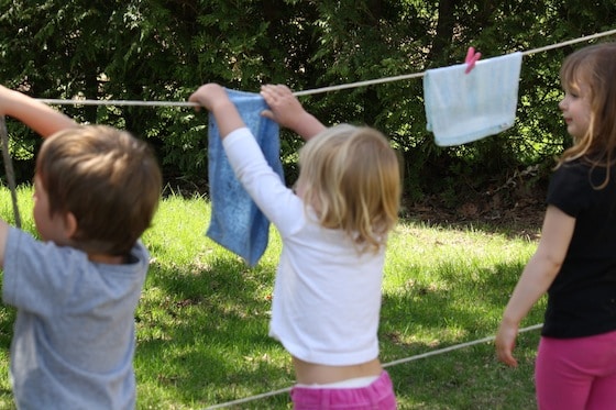 3 preschoolers hanging facecloths on pretend play clothesline