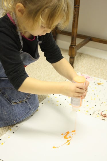 child squeezing paint for pumpkin art