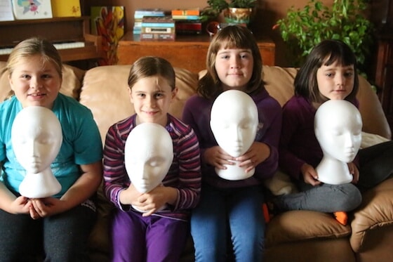 4 kids holding white styrofoam mannequin heads