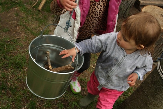 toddler loading up the bucket with sticks