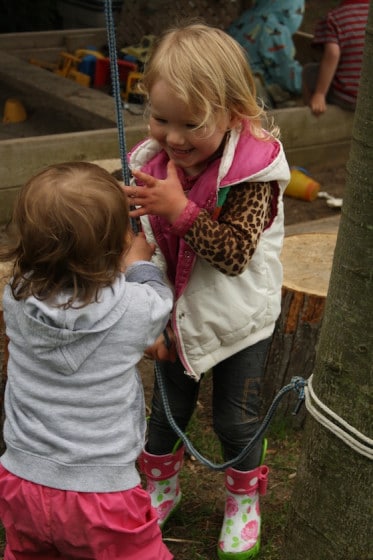 toddler and preschooler working together to lift the bucket