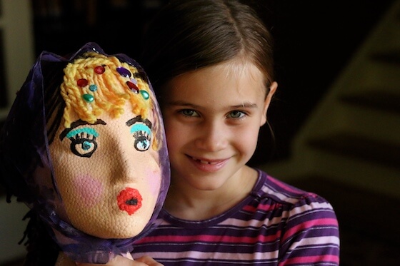 Girl holding decorated styrofoam head